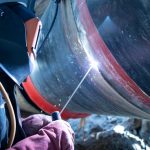 Professional welder welding pipe on a pipeline construction.